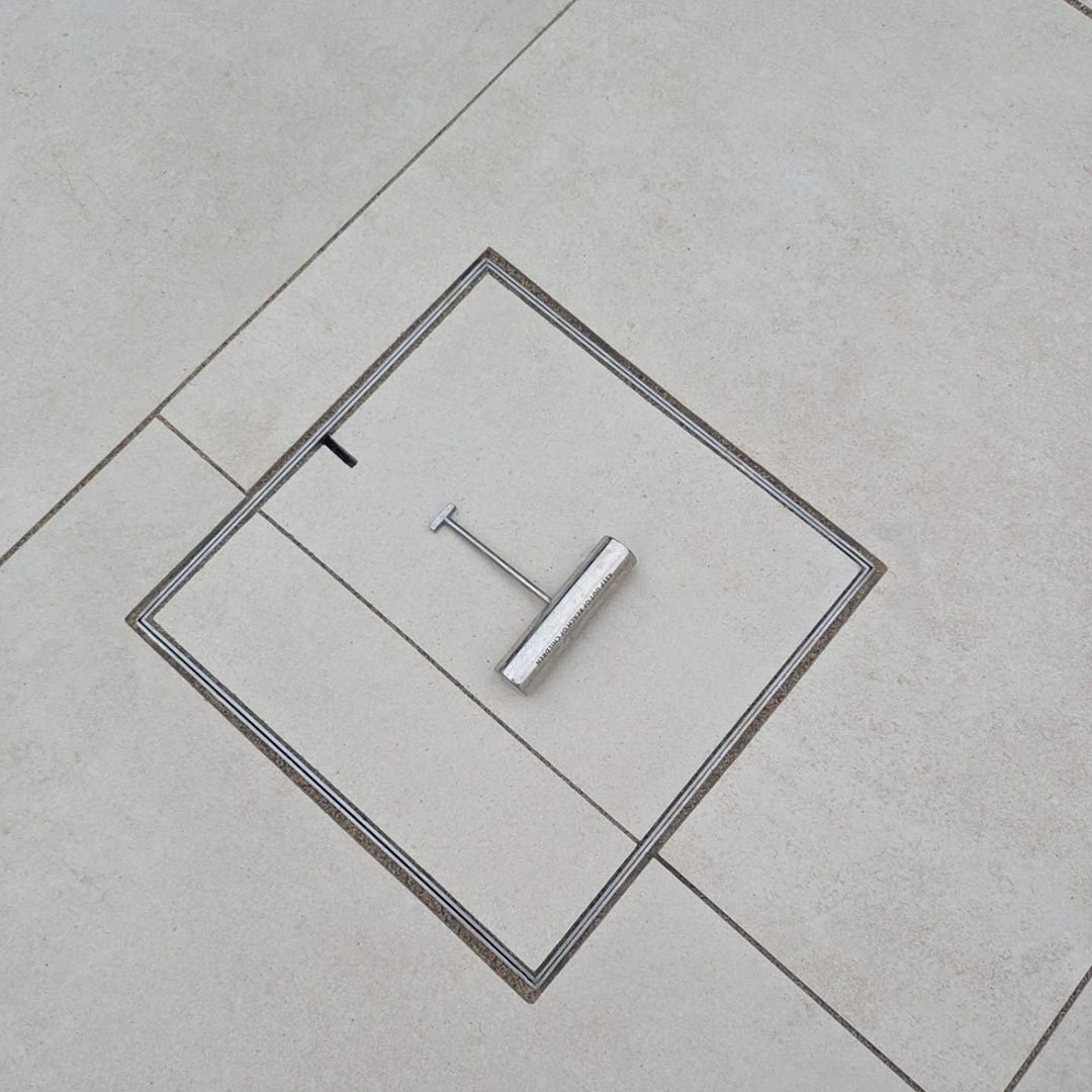 HIDE 8" Access Cover with paving inlay installed, HIDE safety key resting on top ready to be lifted.
