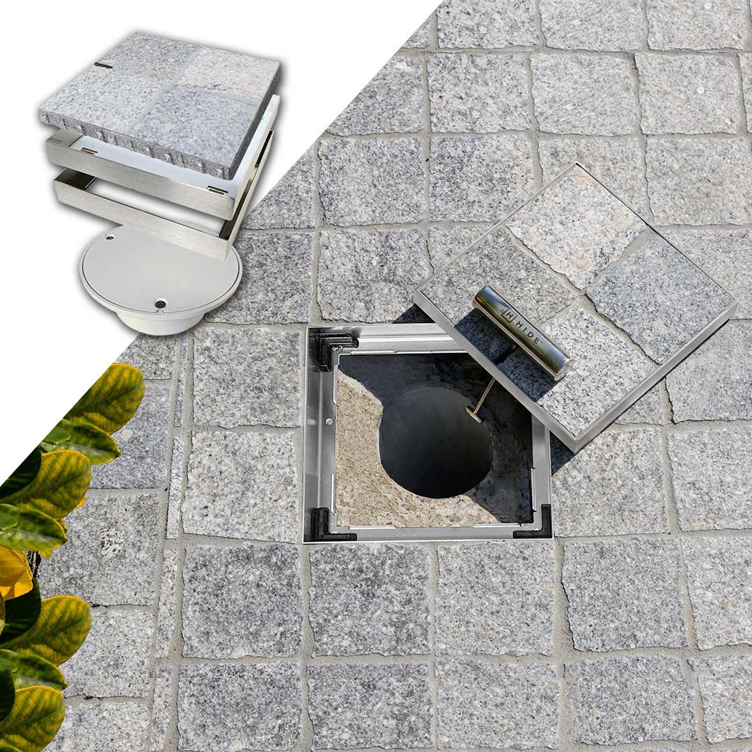 156mm HIDE Access Cover with cobblestone inlay sitting open to view service access pipe below