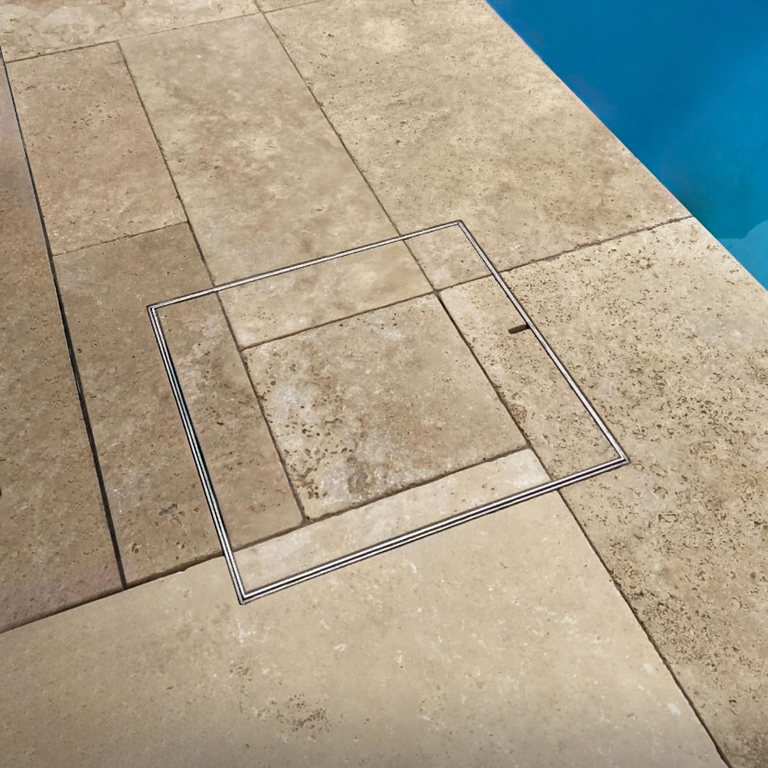 HIDE stainless steel Skimmer Lid with cream paving inlay installed flush and seamless next to swimming pool.