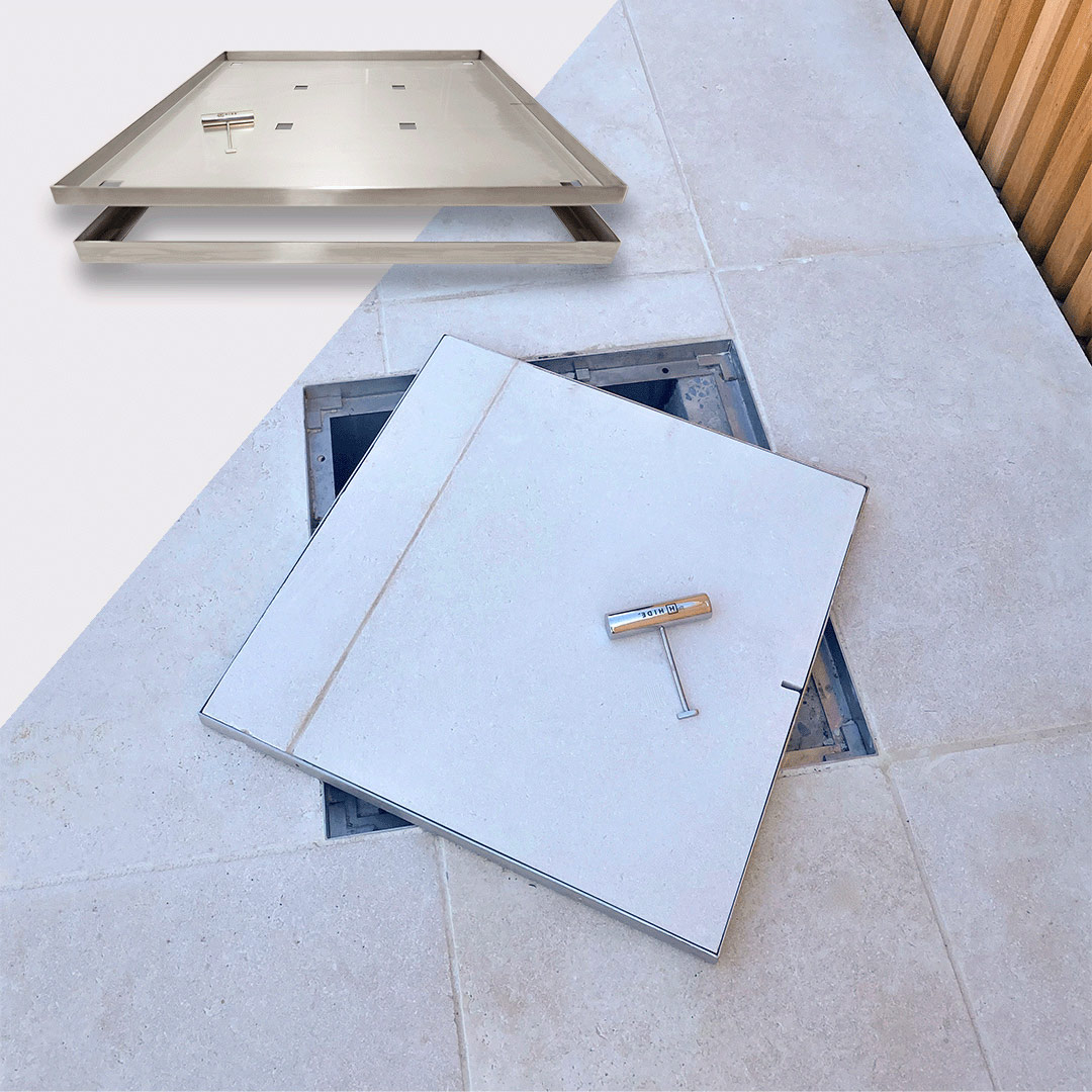 HIDE 656mm Drain Cover installed with white tile inlay, lifted open to view service access point below.